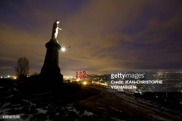 An SOS sign displayed by ArcelorMittal's protesting workers is seen beside the Virgin Mary statue on December 10, 2012 obove the blast furnaces of...