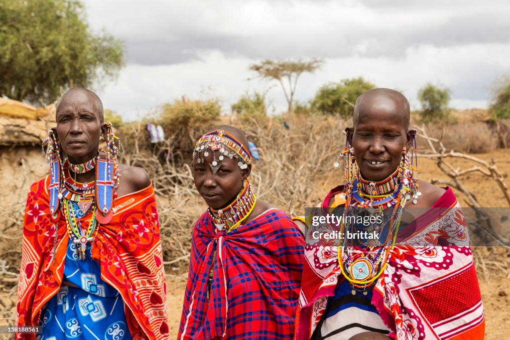 Three Maasai women outside their village.
