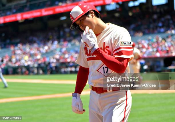 Shohei Ohtani of the Los Angeles Angels takes off his batting gloves after scoring in the first inning against the Seattle Mariners at Angel Stadium...