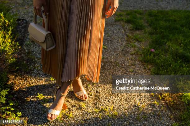 young multiracial woman dressed in elegant dress & heels & holding small purse - black tie party fancy stockfoto's en -beelden