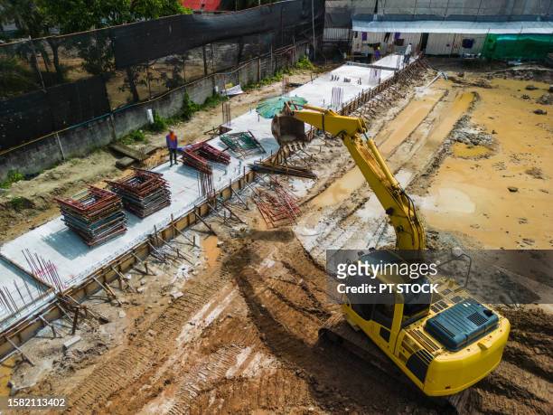 aerial view excavators help load steel scaffolding at structural site - large construction site stock pictures, royalty-free photos & images