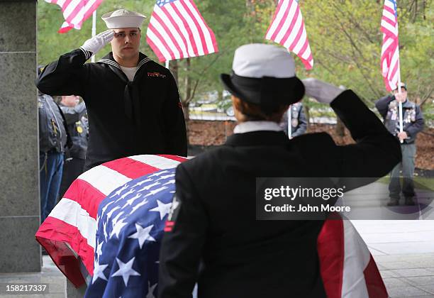 Navy honor guard salutes over the casket of Navy veteran David Maxwell before his burial at the Calverton National Cemetery on December 11, 2012 near...