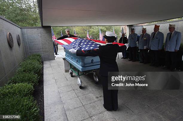 Navy honor guard removes an American flag from the casket of Hurricane Sandy victim David Maxwell before his burial at the Calverton National...