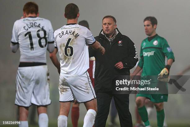 Mark Yates manager of Cheltenham Town shakes hands with Luke Graham of Hereford United after his sides 2-1 extra time victory during the FA Cup with...