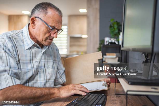 senior men using computer and reading documents at home - one senior man only stock pictures, royalty-free photos & images