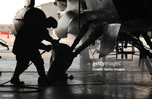 Senior Airman Ryan Fletcher, a dedicated crew chief, 31st Aircraft Maintenance Squadron, hoses down an F-16's main landing gear wheel wells as part...