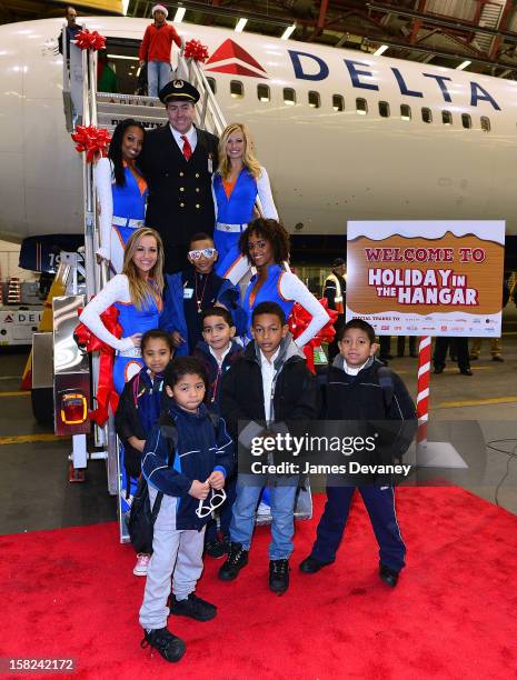 Delta pilot and the Knicks City Dancers pose with children at the 3rd Annual Garden of Dreams Foundation & Delta Air Lines' 'Holiday in the Hangar'...