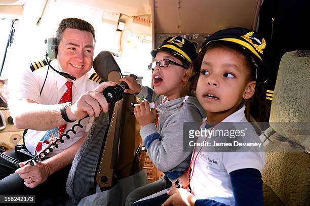 Delta pilot and children attend the 3rd Annual Garden of Dreams Foundation & Delta Air Lines' 'Holiday in the Hangar' event at John F. Kennedy...