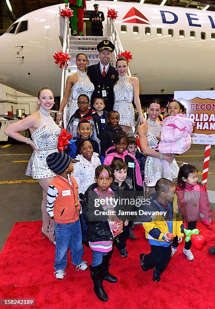 Delta pilot and the Radio City Rockettes pose with children at the 3rd Annual Garden of Dreams Foundation & Delta Air Lines' 'Holiday in the Hangar'...