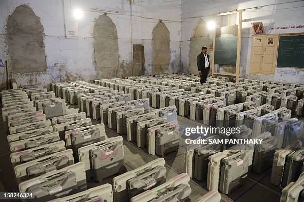 An Indian election monitor stands near Electronic Voting Machines at a distribution centre at Viramgam, some 60 kms from Ahmedabad on December 12,...