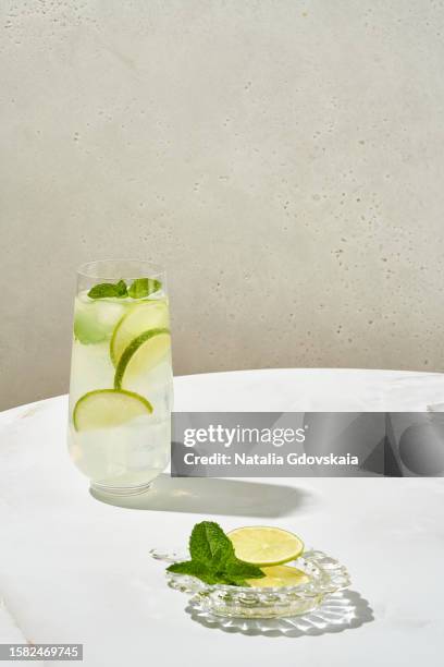 fresh mojito summer lime and mint cocktail with ice cubes. drinking glass of soda drink. cold lemonade recipe. sunlight, white marble table, still-life, lifestyle - lime juice stock pictures, royalty-free photos & images