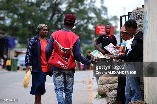 Vendor hands out a Christmas shopping catalogue in Johannesburg's Alexandra Township on December 12, 2012. AFP PHOTO / ALEXANDER JOE