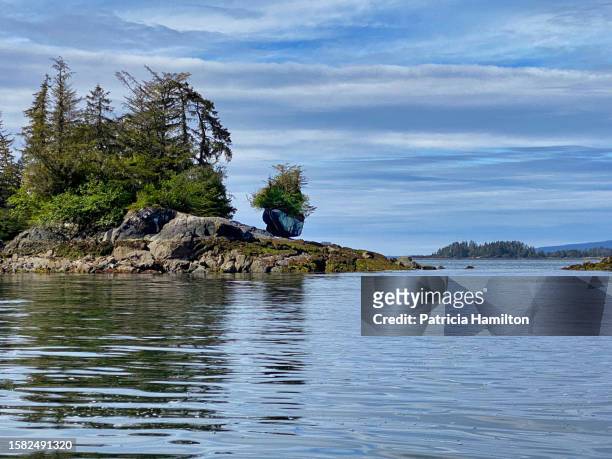 island in sitka sound with a balancing rock. - alaska coastline stock pictures, royalty-free photos & images