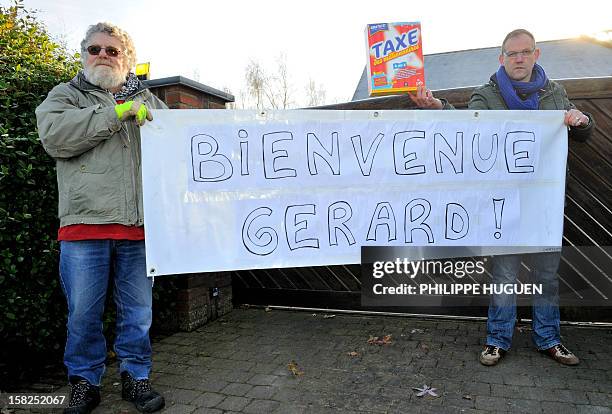 Belgian Workers Party militants pose on December 12, 2012 with a placard, reading :"Welcome Gerard!," and a box looking like laundry detergent,...