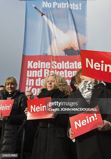 Activists from Germany's Left Party display placards reading "no" as they pose in front of a banner reading: "No Patriots, no missiles or soldiers in...