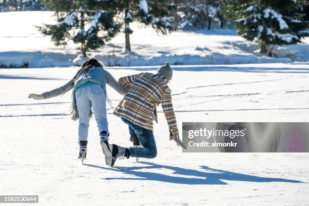 couple ice skating on frozen lake - man-falling-forward stock pictures, royalty-free photos & images