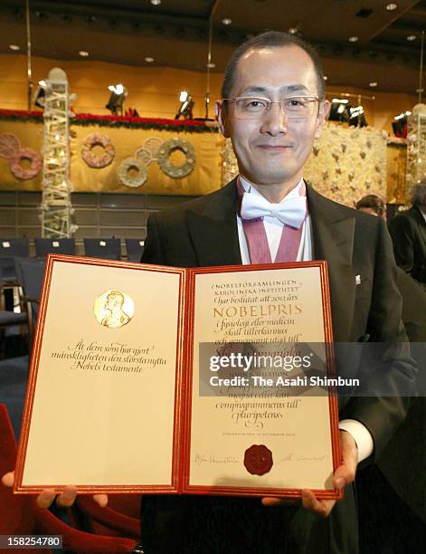 Nobel Prize in Medicine laureate Shinya Yamanaka poses for photographs with his award certificate after the award ceremony at Concert Hall on...