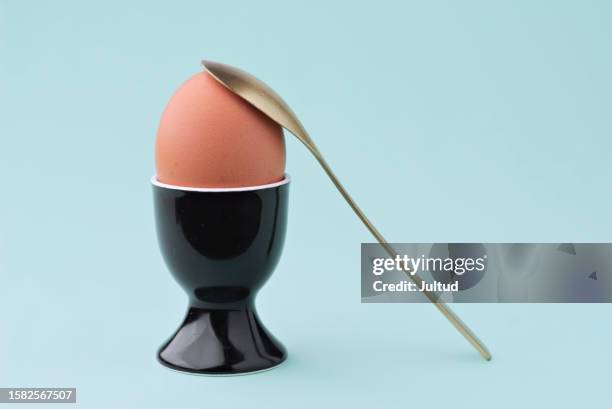 whole eggs in black porcelain cup with golden spoon - gekochtes ei stock-fotos und bilder