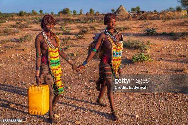 deux jeunes femmes africaines transportant l’eau du puits, ethiopie, afrique - hamar photos et images de collection