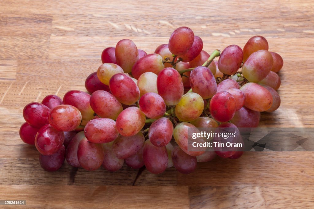 A bunch of red grapes on a wooden chopping board