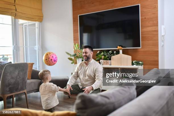 small toddler and father playing with ball at home - gag ball stock pictures, royalty-free photos & images