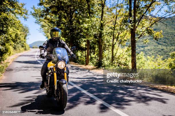 biker with full safety gear enjoys ride on country road - biker helmet stock pictures, royalty-free photos & images