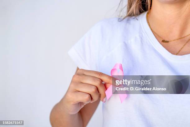 close up of woman showing pink ribbon symbolizing breast cancer - pink october stock pictures, royalty-free photos & images