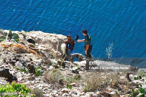 Guardia Civil officer with one of the Syrian migrants who has swum to the coast of Ceuta, in the Sarchal neighborhood, on 31 July, 2023 in Ceuta,...
