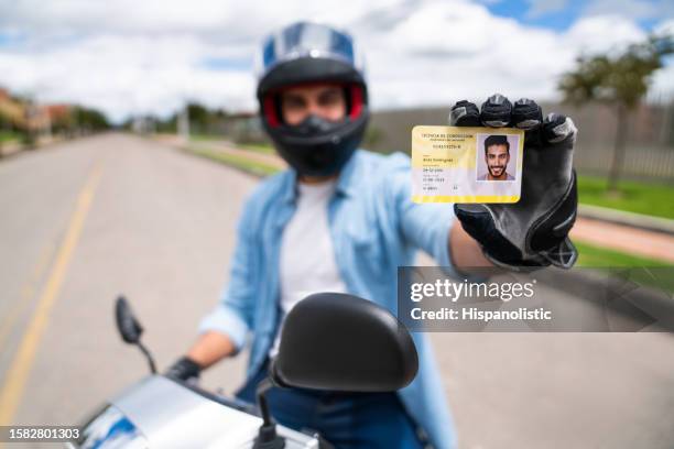 motociclista in possesso della patente di guida - patente di guida foto e immagini stock