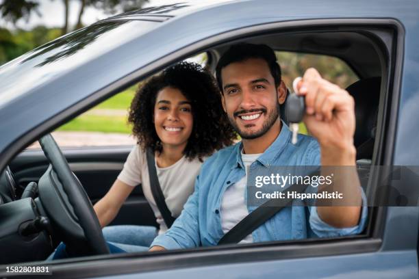 feliz pareja sosteniendo las llaves de su nuevo coche - car ownership fotografías e imágenes de stock