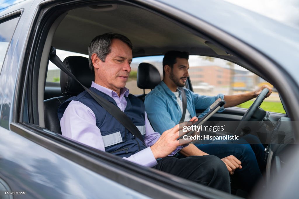 Driving instructor using a tablet while grading a man's driving test