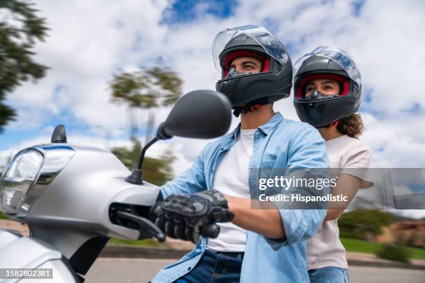 jeune couple conduisant sa moto à l’extérieur - gants de sport photos et images de collection