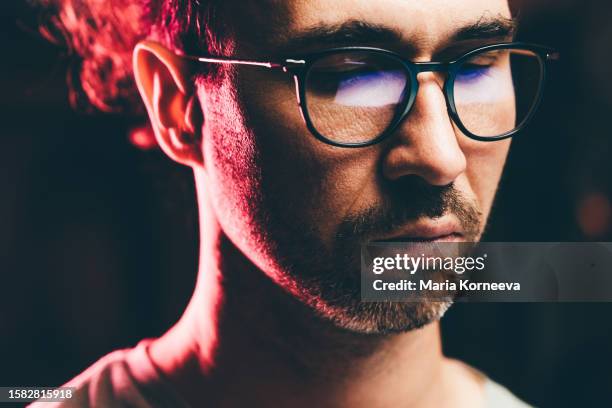 men wearing glasses watching something on his laptop at home at the night. young man using a laptop, reflection of a website in his glasses, close up. - reading glasses isolated stock pictures, royalty-free photos & images