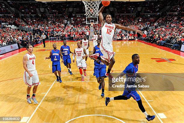 Sam Thompson of the Ohio State Buckeyes soars in for a slam dunk over Cedric Smith of the Savannah State Tigers in the second half on December 12,...