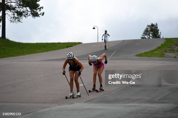 unidentified athletes train with ski rollers on asphalt track cross-country skiing - biathletes training at holmenkollen in oslo. - cross country skiing bildbanksfoton och bilder