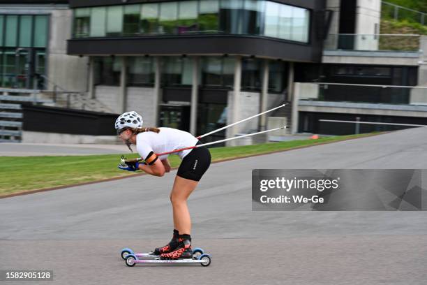 unidentified athletes train with ski rollers on asphalt track cross-country skiing - biathletes training at holmenkollen in oslo. - rollerskis stockfoto's en -beelden