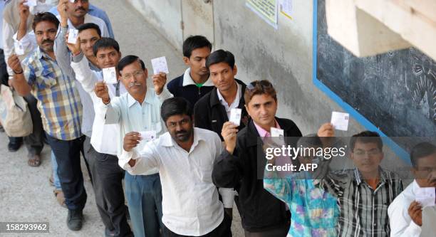 Indian voters display their identity cards prior to casting of votes in state assembly elections at Sanand some 30kms. From Ahmedabad on December 13,...