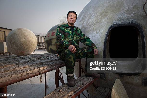 China-society-offbeat-apocalypse,FOCUS by Tom Hancock This photo taken on December 11, 2012 shows farmer Liu Qiyuan posing with survival pods that he...