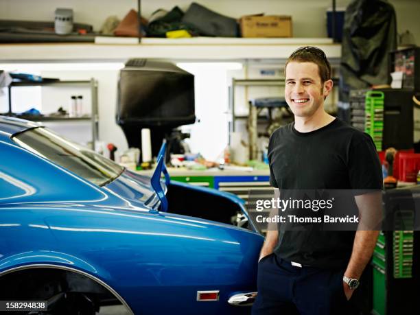 mechanic standing in garage next to classic car - restoration style photos et images de collection