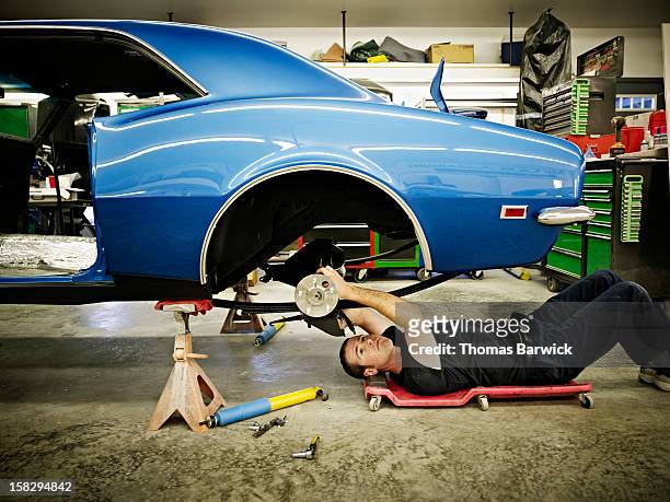 mechanic lying on floor in garage working on car - machine part stock pictures, royalty-free photos & images