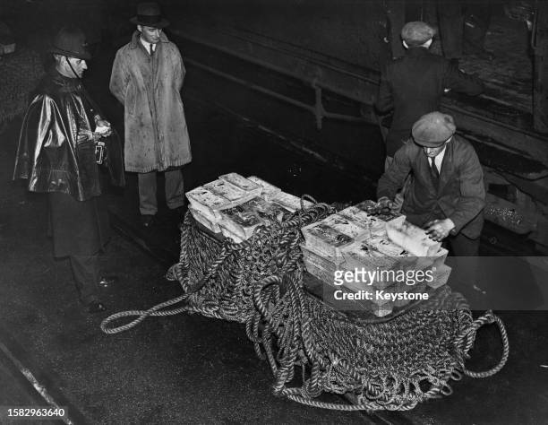 Group of people, including a policeman, alongside three thousand bars of silver on the dockside waiting to be hoisted onboard the 'SS Manhattan',...