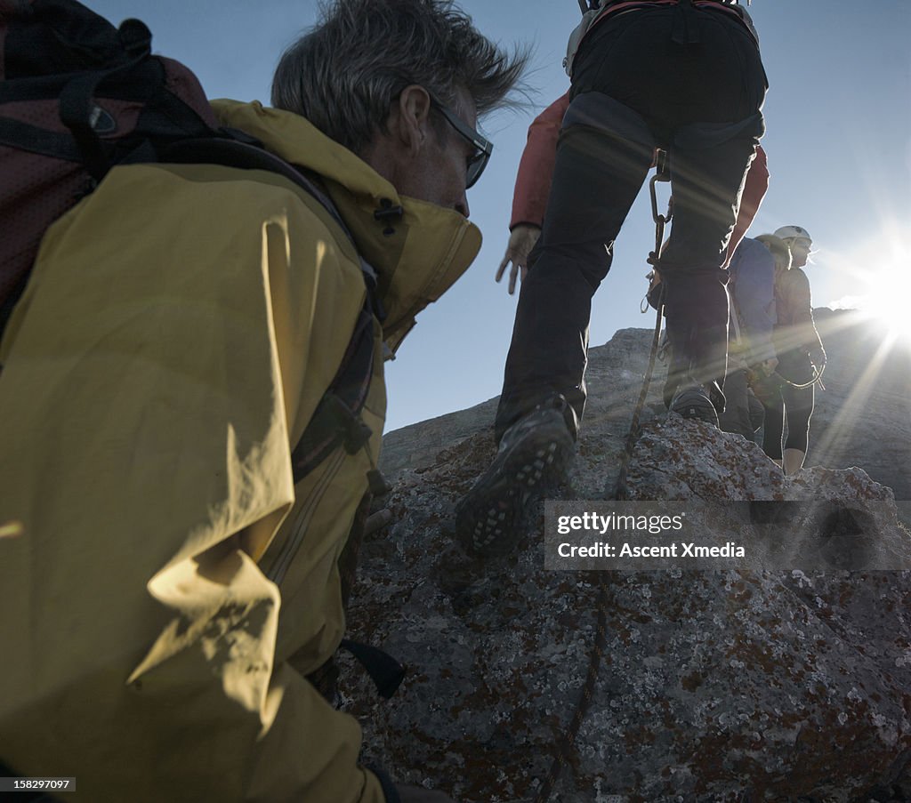 Climbers approach summit of mountain, sunrise