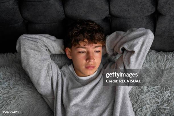 joven adolescente acostado en la cama preocupado. - teen boy looking down fotografías e imágenes de stock