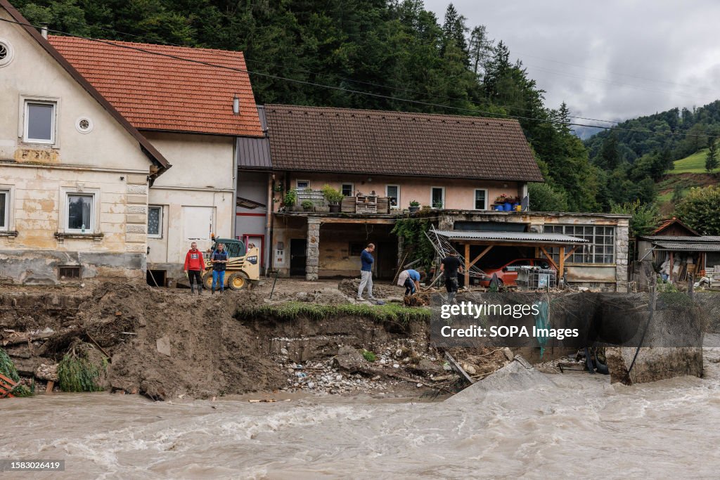 People clean up the debris and mud from a damaged house and...