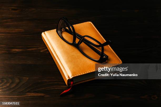 yellow diary and glasses on a dark wooden background. - book on table foto e immagini stock
