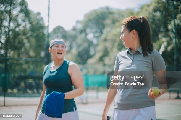 2 asian chinese female tennis players walking out from tennis court after game on weekend morning - game 2 2 stock pictures, royalty-free photos & images