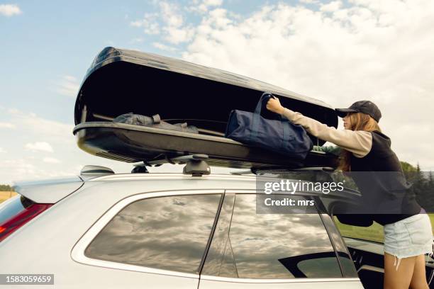 teenage girl taking bag from car roof box - car roof box stock-fotos und bilder