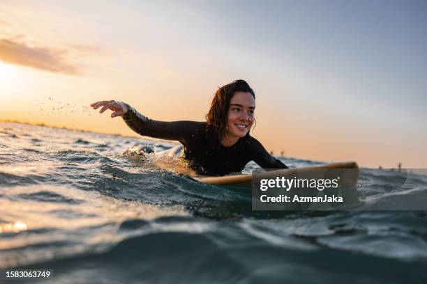 cheerful amateur female surfer enjoying her early morning surf session alone - surfing stock pictures, royalty-free photos & images