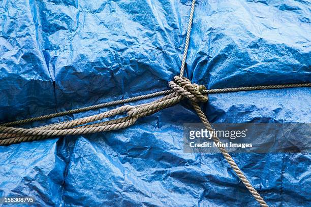 a blue tarpaulin covering stacked commercial fishing nets on the dockside at fisherman's wharf, seattle.  - tarpaulin stock pictures, royalty-free photos & images