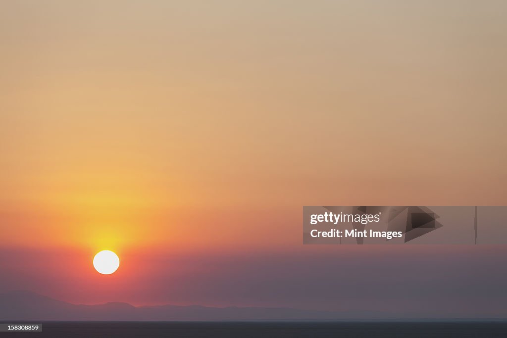 The rising sun over flat desert landscape at dawn in Nevada.